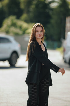Dynamic portrait of woman spinning around in black blazer outdoors
