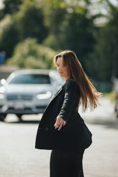 Dynamic portrait of woman spinning around in black blazer outdoors