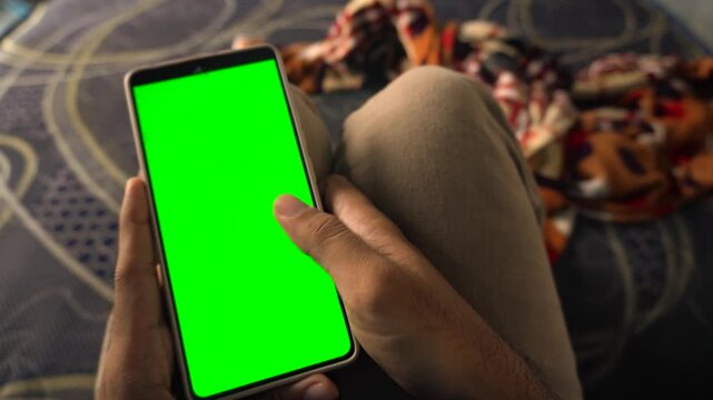 Dynamic green screen transition effect on a smartphone held vertically by a person scrolling social media feeds, capturing mobile browsing, app use, and digital technology.