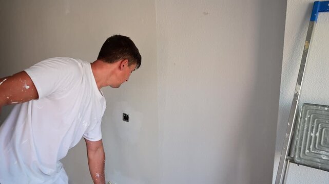 Professional painter using a roller to paint a wall white