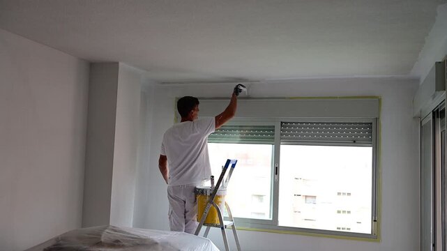 Professional house painter painting a room's ceiling white