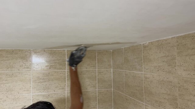 Plasterer applying putty on a ceiling corner during renovation work