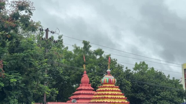 Colorful Hindu Temple Shikharas with Flags Under Dramatic Monsoon Sky

