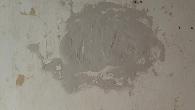 Worker applying filler plaster to an old wall with a spatula to repair it