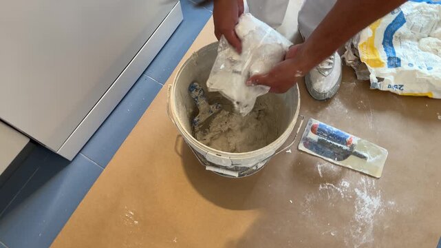 Construction worker preparing plaster mixture in a bucket