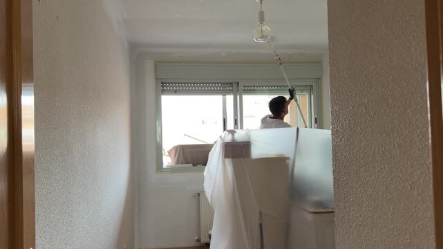 Man painting the ceiling with a roller extension pole