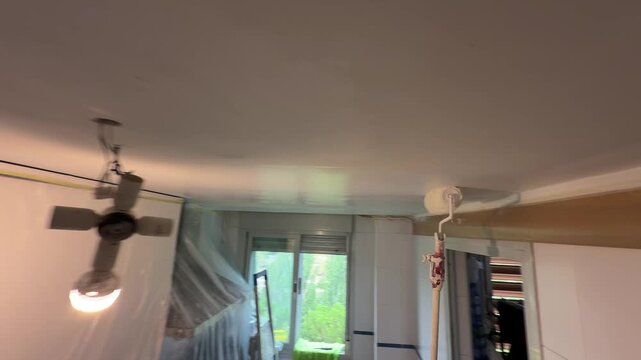 Professional painter using a roller to paint a ceiling white