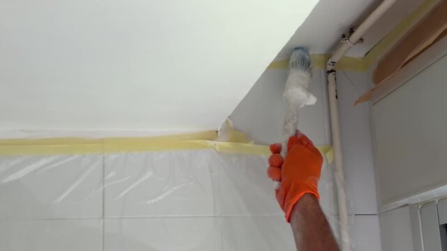 Professional worker painting a ceiling with a brush