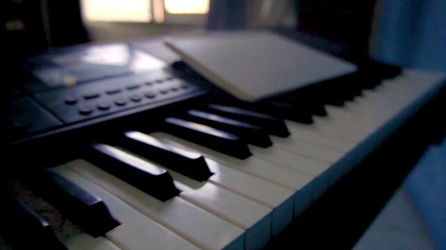 Dynamic backward camera movement revealing black and white piano keys with a notebook on top, capturing musical creation, studio sessions, and melody production concepts.
