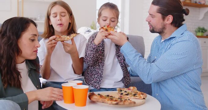 Happy family with kids enjoys eating pizza for dinner or lunch at home living room, celebrating together in a cozy domestic setting filled with warmth and joy during a delightful meal.