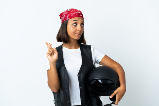 Young woman holding a motorcycle helmet isolated on white with fingers crossing and wishing the best
