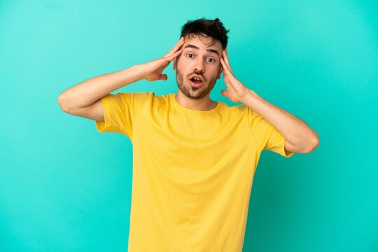 Young caucasian man isolated on blue background with surprise expression