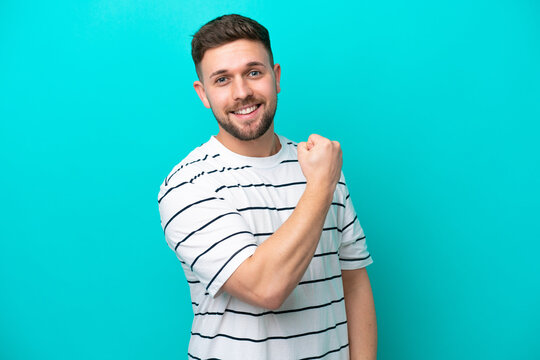 Young caucasian man isolated on blue background celebrating a victory