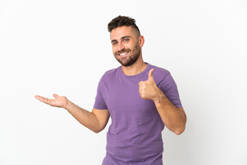 Naklejka premium Caucasian man isolated on white background holding copyspace imaginary on the palm to insert an ad and with thumbs up