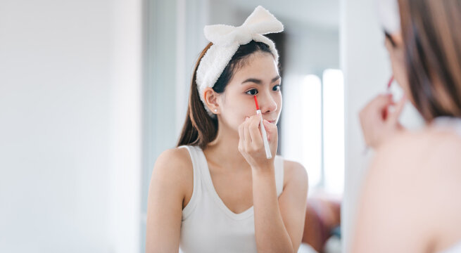 Young adult southeast asian woman makeup and face skincare before mirror in dress room at home