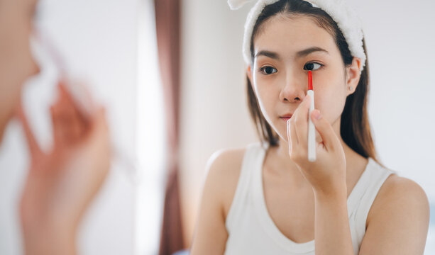 Young adult southeast asian woman makeup and face skincare before mirror in dress room at home