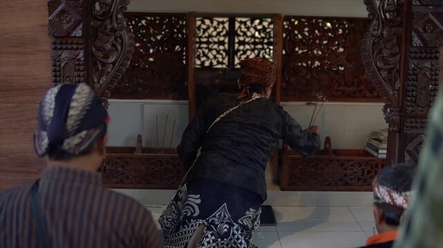 People in traditional Javanese attire praying in a sacred wooden temple setting in 4k video.