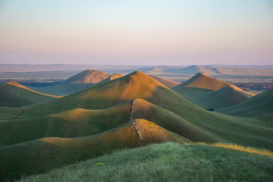 Summer sunset at Dolgiye Mountains in the Orenburg region, Russia. Hilly terrain, mountain fields. The beginning of the Ural Mountains.