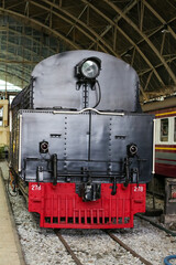 Classic black steam locomotive with red front detail on railway tracks © khomkrit