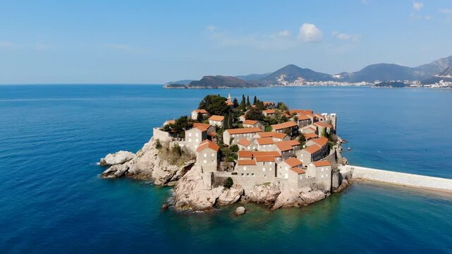 Aerial view of Sveti Stefan featuring the iconic fortified island surrounded by the crystal clear Adriatic Sea on the beautiful coast of Montenegro.