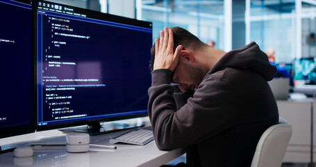 Fototapeta premium Young Software Engineer Looks Tired And Stressed While Coding