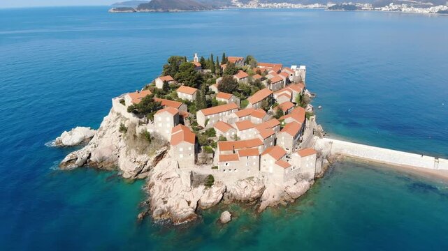 Aerial view of the iconic island of Sveti Stefan surrounded by the crystal clear Adriatic Sea on the beautiful Montenegrin coast.