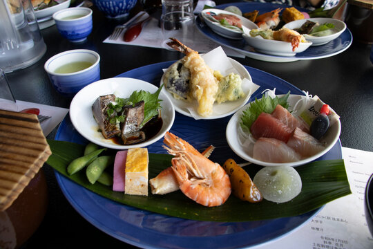 sashimi, tempura, grilled fish with garnish, slices of egg and prawn, edamame, and a mochi dessert