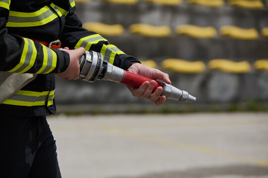 Firefighter Holding Fire Hose Nozzle During Training Drill With Protective Uniform and Reflective Stripes