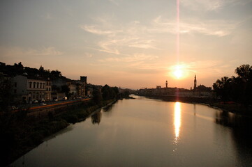Golden sunset reflecting on the Arno River beside historic architecture in Florence, Italy. A tranquil Tuscan cityscape for travel and romantic destination themes. © Before Noon
