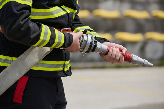 Firefighter Holding Fire Hose Nozzle in Reflective Turnout Gear During Emergency Training Exercise