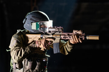 Naklejka premium Tactical Soldier Aiming Assault Rifle While Wearing Helmet Visor And Body Armor In Low Light