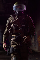 Obraz premium Armed Tactical Soldier In Protective Helmet And Visor Walking Through Dim Urban Environment