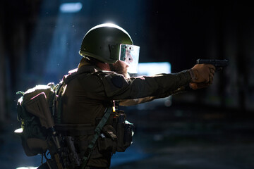 Obraz premium Tactical Soldier Aiming Handgun in Dark Urban Environment Wearing Helmet and Protective Gear