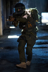 Fototapeta premium Tactical Soldier In Urban Combat Gear Aiming Assault Rifle Inside Dark Abandoned Building