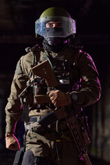 Obraz premium Armed Tactical Soldier in Riot Helmet and Body Armor Holding Assault Rifle in Low Light