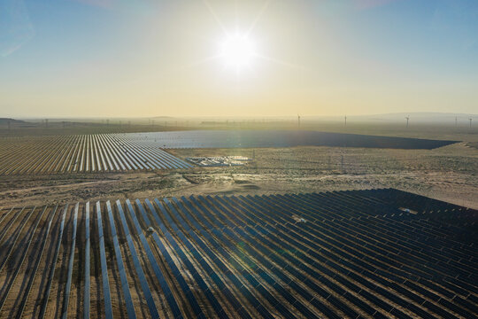 Solar PV panels and wind turbine power plant at sunrise/sunset, new energy