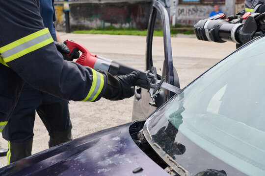 Firefighters Using Jaws of Life For Car Extrication During Emergency Rescue At Accident Scene