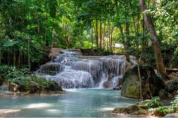 Tropical waterfall cascading through lush rainforest. Serene jungle oasis with crystal-clear stream and vibrant greenery. © Ali Ahmad