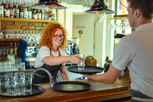 Happy baristas working together serving customers behind bar