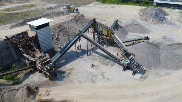 Aerial view of stone crushing and aggregate processing plant with conveyor belts, gravel stockpiles, and heavy machinery