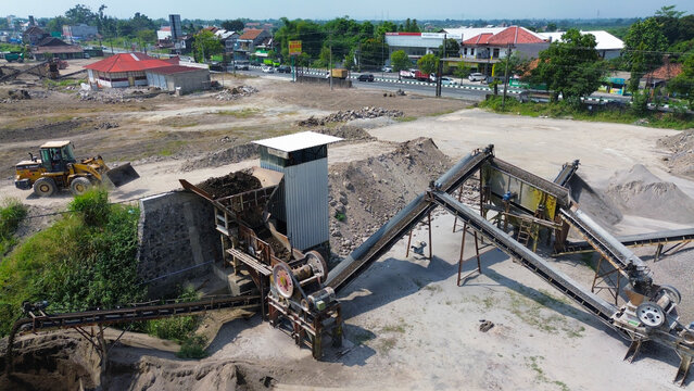 Aerial view of stone crushing and aggregate processing plant with conveyor belts, gravel stockpiles, and heavy machinery