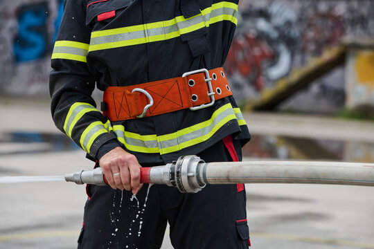 Firefighter Holding Hose in Turnout Gear Spraying Water During Urban Training Exercise