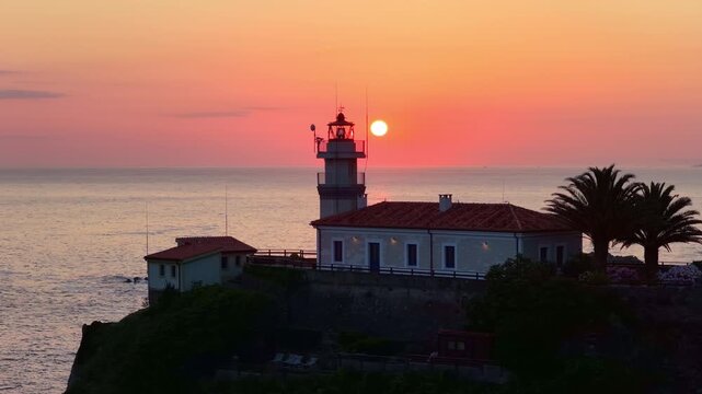 sunrise drone shot of lighthouse on a rock in Cudillero, Asturias, Atlantic coast of Spain, Spanish ocean coast drone view, orbiting shot of a lighthouse on a rock at sunrise, cinematic travel