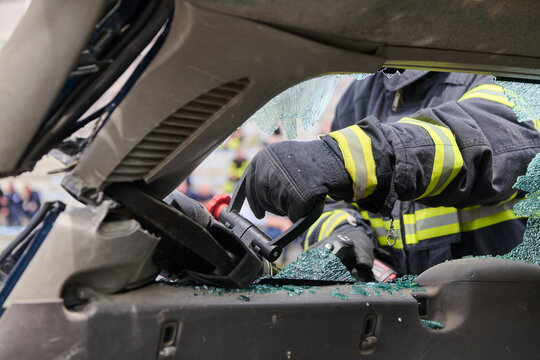 Firefighter Performing Vehicle Extrication With Hydraulic Rescue Tool Through Broken Car Window During Emergency Response