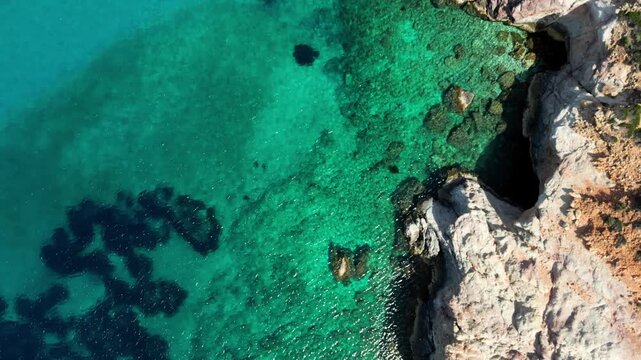 Overhead Shot tracing the cliffs of Plathiena in Milos, Greece. Showing the stunning crystal clear waters. Shot on a 4k at 60 fps on a DJI Mini 3 Pro in D-Log Film Colorgraded