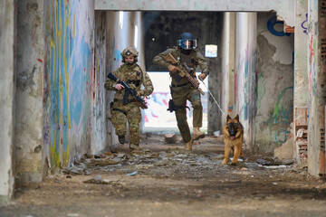 Obraz premium Armed Military Soldiers With Tactical Dog Conducting Urban Search And Clearance Operation In Abandoned Building