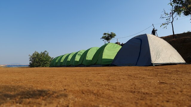 Row of camping tents on hilltop under clear blue sky outdoor adventure travel concept