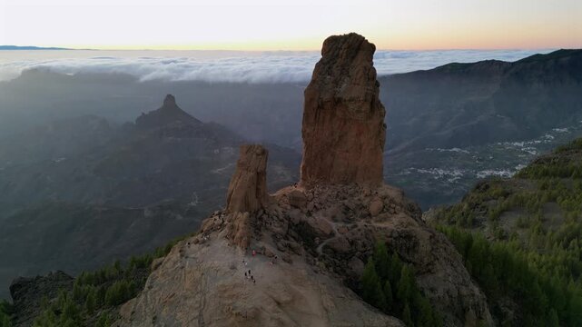 Magnificent aerial view of Roque Nublo, an iconic volcanic rock formation in Gran Canaria. Hikers enjoying the majestic sunset over the mountains