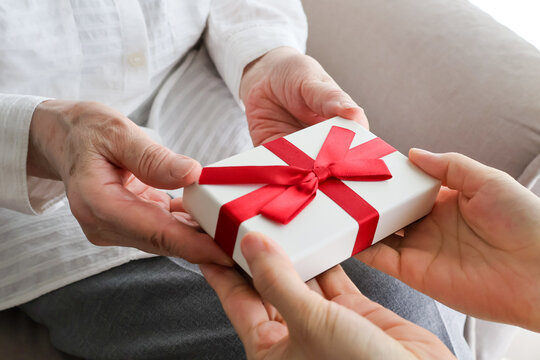 Elderly woman receiving a wrapped gift from family member