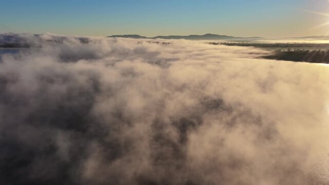 Aerial video of Lake Keepit Dam blanketed by morning fog in NSW, Australia. Low cloud drifts across the reservoir and surrounding landscape